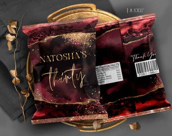 Puede incluir: Dos bolsas de regalo para fiestas con un diseño burdeos y dorado. La bolsa delantera dice "Natosha's Thirty" en escritura dorada. La bolsa trasera tiene un mensaje de "Gracias" y un código de barras. Las bolsas están sobre una bandeja dorada.