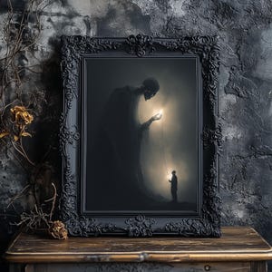 May include: A framed artwork with a dark, gothic theme. The black frame surrounds a surreal image of a skeletal figure offering light to a small person. The artwork is displayed on a wooden surface.