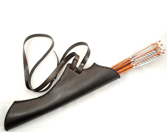 May include: A brown leather quiver with a strap for carrying arrows. The quiver is filled with a set of arrows with white fletching.