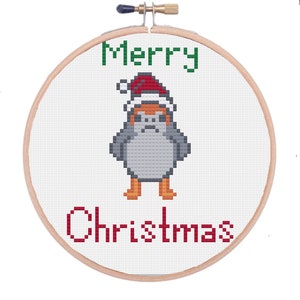 Könnte beinhalten: Ein weißer Kreuzstich-Stickrahmen mit einem grünen "Merry" und einem roten "Christmas"-Text. In der Mitte befindet sich ein Pixelbild eines Star Wars-Charakters mit einem roten Weihnachtsmann-Hut.