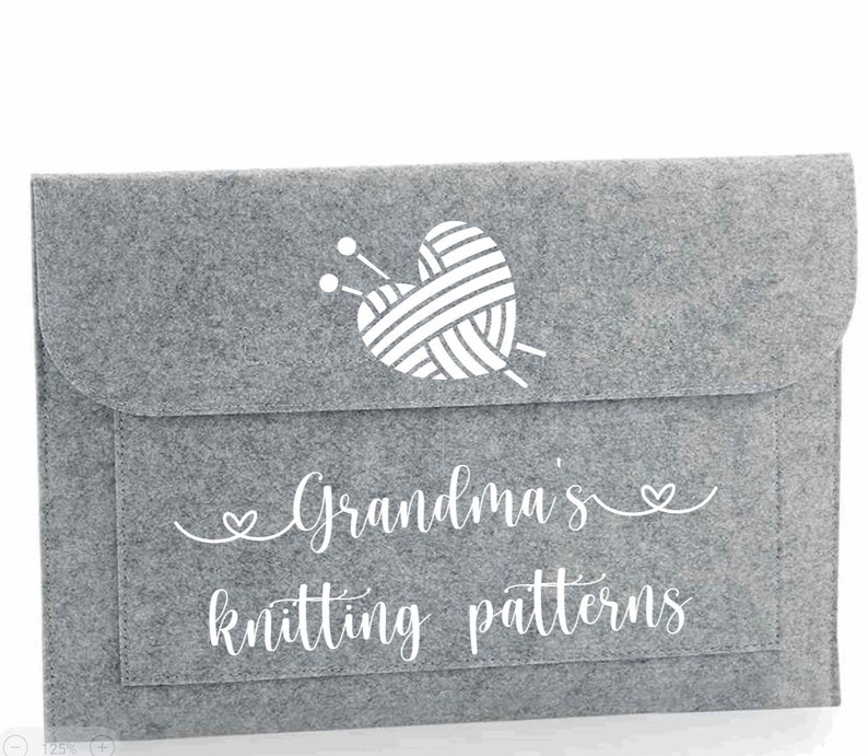 May include: Grey felt storage envelope with a white heart-shaped yarn ball and knitting needles design. The text "Grandma's knitting patterns" is printed on the front.