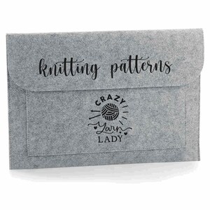 K&ouml;nnte beinhalten: Graue Filz-Ordnungstasche f&uuml;r Strickmuster mit dem Text "knitting patterns" und einem Design, das "Crazy Yarn Lady" mit einer Wollkn&auml;uel und Stricknadeln sagt.