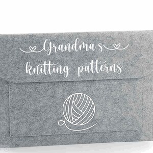 May include: Grey felt storage envelope with a white outline of a ball of yarn and the text "Grandma's knitting patterns"