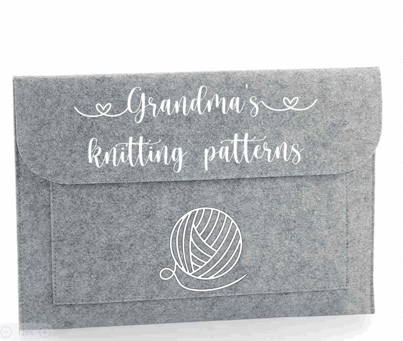 May include: Grey felt storage envelope with a white outline of a ball of yarn and the text "Grandma's knitting patterns"