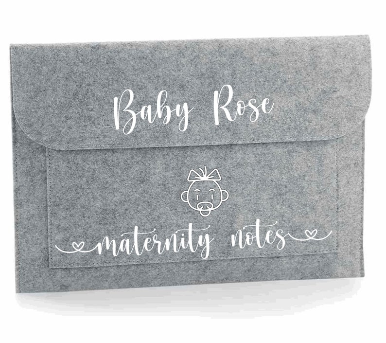 May include: Grey felt folder with a pocket and a white outline of a baby with a bow and dummy. The text "Baby Rose" and "maternity notes" is written in white cursive.