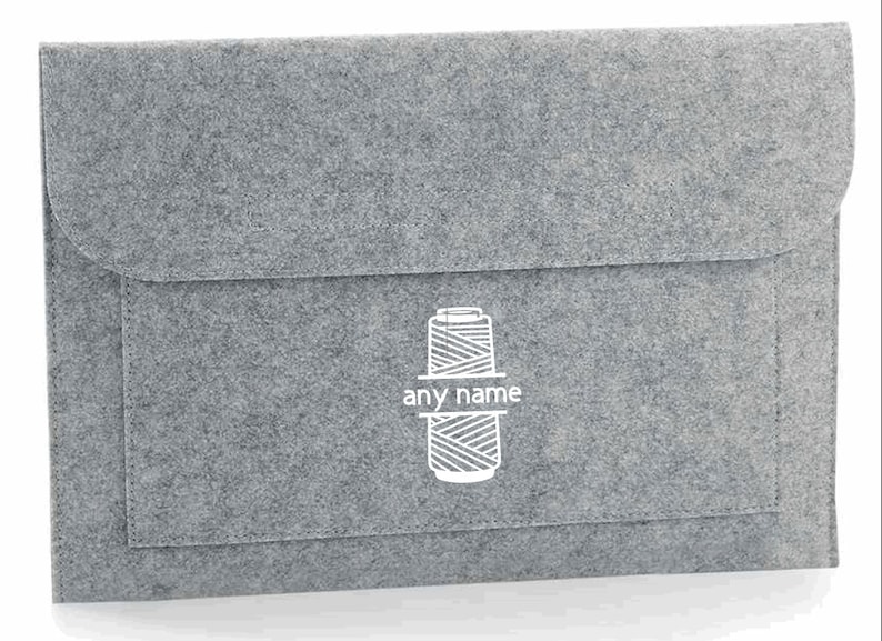 K&ouml;nnte beinhalten: Graue Filz-Laptoptasche mit einem wei&szlig;en Garnrollen-Design und dem aufgedruckten Text "any name".