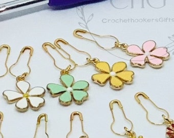 May include: A set of 10 gold safety pins with colorful flower charms. The charms are in pink, yellow, green, and white. The charms are attached to the safety pins with a gold loop.