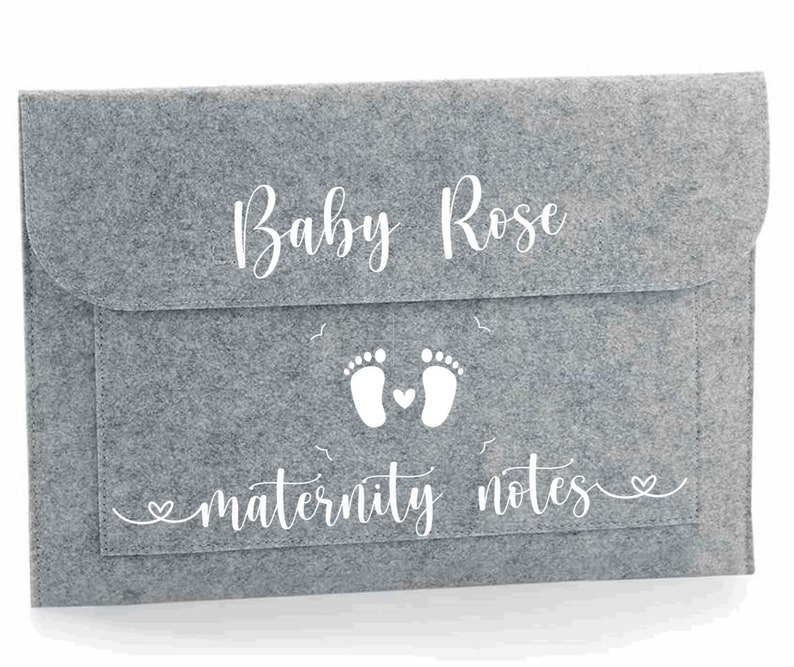 May include: Grey felt folder with a white design. The design includes the text "Baby Rose" and "maternity notes" with a pair of footprints and a heart.