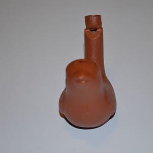 May include: A terracotta whistle shaped like a bird. The whistle has a small hole on the top for blowing.