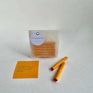Puede incluir: Un conjunto de iniciadores de conversación amarillos en una bolsa de plástico transparente con una etiqueta blanca que dice "Tischgespräche" para "Klasserbellus". Los iniciadores de conversación están enrollados y listos para usar. También se incluye una tarjeta amarilla con el texto "Faszinieren dich die Geschichten von Genies oder die von einfachen Menschen?"