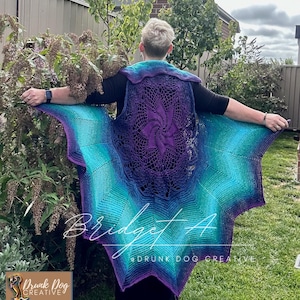 May include: A handmade crochet vest in shades of purple, teal, and blue. The vest features a central spiral design and a scalloped edge. The text "Bridget A" and "@Drunk Dog Creative" are visible.