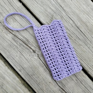 May include: A lavender crocheted phone case with a handle. The case is made with a delicate stitch pattern.