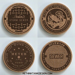 May include: Four round cork coasters with different designs. The first coaster has a brown and black design with the text "Avalon Storm Sewer" and "Made in USA". The second coaster has a brown and black design with the text "Cape May County D.P.W. Dump No Waste Drains to Waterways". The third coaster has a brown and black design with the text "Ocean City Water Service Co. Meter The Ford Meter Box Wabash Ind.". The fourth coaster has a brown and black design with the text "Wildwood Watch The Tramcar Please Sewer".
