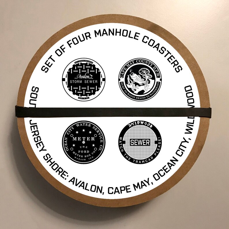 May include: A set of four round brown coasters with white manhole covers printed on them. The coasters feature the text "Set of Four Manhole Coasters" and the names of the towns "Avalon, Cape May, Ocean City, Wildwood".