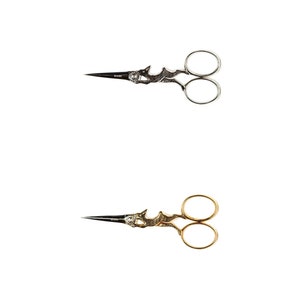 May include: Two pairs of decorative scissors with ornate handles. One pair is silver and the other is gold.