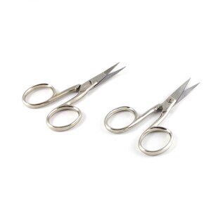 May include: Two pairs of silver-toned cuticle scissors with pointed tips. The scissors are open and ready to use.