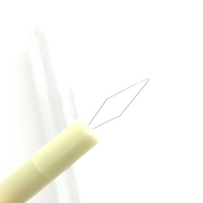May include: A white plastic needle threader with a diamond-shaped metal loop at the end.