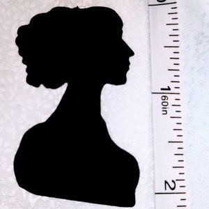 May include: A black silhouette of a woman's profile, showcasing her hair and neckline. A white measuring tape with inch markings is positioned next to the silhouette, indicating its size.