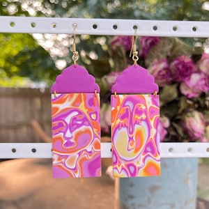 May include: A pair of pink and orange swirl pattern earrings with a pink cloud-shaped top.