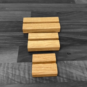 Puede incluir: Tres elevadores de exhibici&oacute;n de madera, cada uno con una altura diferente, hechos de madera natural de color marr&oacute;n claro. Los elevadores est&aacute;n apilados uno encima del otro, creando una exhibici&oacute;n escalonada.
