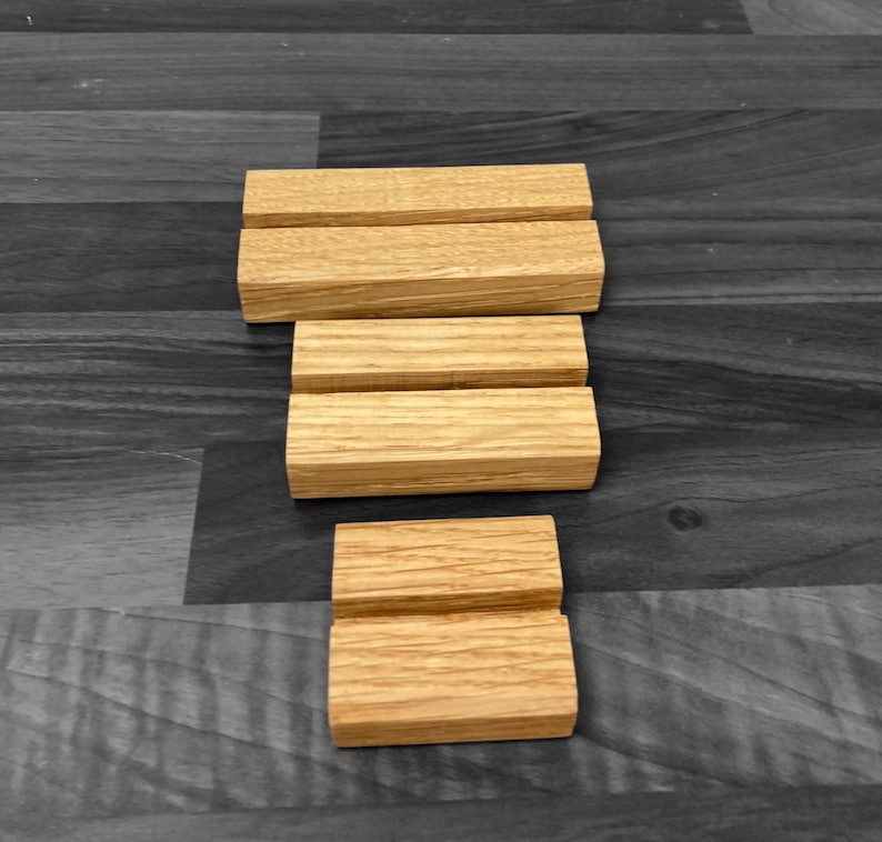 Puede incluir: Tres elevadores de exhibici&oacute;n de madera, cada uno con una altura diferente, hechos de madera natural de color marr&oacute;n claro. Los elevadores est&aacute;n apilados uno encima del otro, creando una exhibici&oacute;n escalonada.