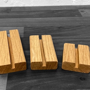 Puede incluir: Tres soportes de exhibici&oacute;n de madera de diferentes tama&ntilde;os, cada uno con una ranura en el centro. Los soportes est&aacute;n hechos de madera marr&oacute;n claro y tienen un acabado natural.