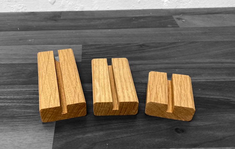 Puede incluir: Tres soportes de exhibici&oacute;n de madera de diferentes tama&ntilde;os, cada uno con una ranura en el centro. Los soportes est&aacute;n hechos de madera marr&oacute;n claro y tienen un acabado natural.
