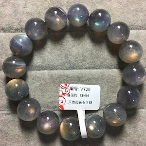 May include: A bracelet made of round, polished labradorite beads with iridescent flashes of blue, gold, and green. A white rectangular tag is attached, displaying the text "编号: VY20", "直径约: 13MM", and "天然拉长石手链".