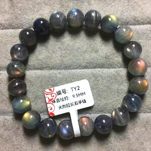 Op de afbeelding: Een cirkelvormige armband gemaakt van gepolijste, ronde labradoriet kralen met iriserende flitsen van blauw, goud en oranje. Een wit rechthoekig label is bevestigd, bedrukt met de tekst: 编号: TY2, 珠直径约: 9.5MM, 天然拉长石手链.
