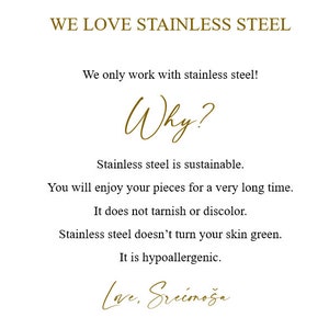 Op de afbeelding: Een witte achtergrond met gouden tekst die "WE LOVE STAINLESS STEEL" luidt. De tekst hieronder legt uit waarom roestvrij staal een goed materiaal is voor sieraden. De tekst luidt: "We werken alleen met roestvrij staal! Waarom? Roestvrij staal is duurzaam. Je zult lang plezier hebben van je stukken. Het verkleurt niet en vervaagt niet. Roestvrij staal verkleurt je huid niet groen. Het is hypoallergeen. Love, Srećmoža"