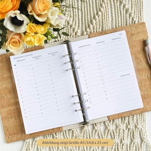 Op de afbeelding: Een witte A5-planner met een transparante plastic binder. De planner heeft een wekelijkse lay-out met een aparte sectie voor elke dag van de week. De planner is open voor december 2024 en januari 2025.