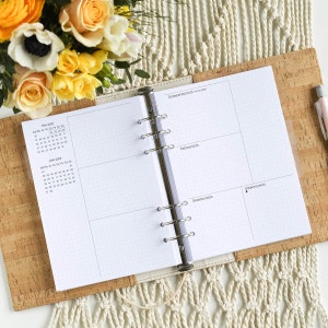 Op de afbeelding: Een witte planner met een kurken omslag en een ringband. De planner heeft een maandelijkse kalender voor mei en juni 2023. De dagelijkse pagina's zijn verdeeld in vier secties: donderdag, vrijdag, zaterdag en zondag.