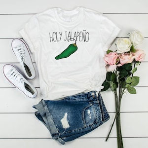 May include: White t-shirt with the text "HOLY JALAPE&Ntilde;O" and a green jalapeno pepper graphic.