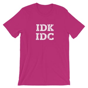 May include: A pink t-shirt with the text "IDK IDC" in white distressed lettering.