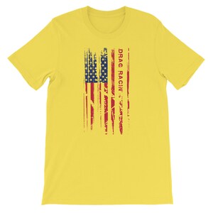 May include: Yellow short-sleeved t-shirt featuring a distressed American flag design and the text "DRAG RACIN'" in red.