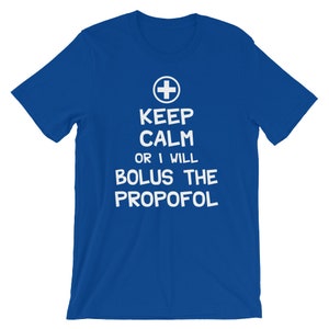 Puede incluir: Una camiseta azul real con texto blanco que dice "Keep Calm or I Will Bolus the Propofol". Un s&iacute;mbolo de cruz m&eacute;dica blanca est&aacute; por encima del texto.