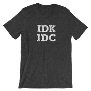 May include: Dark heather grey t-shirt with white text that reads "IDK IDC" in a distressed font.