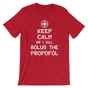 Puede incluir: Camiseta roja con texto blanco que dice "Keep Calm or I Will Bolus the Propofol". Un signo m&aacute;s rojo est&aacute; por encima del texto.