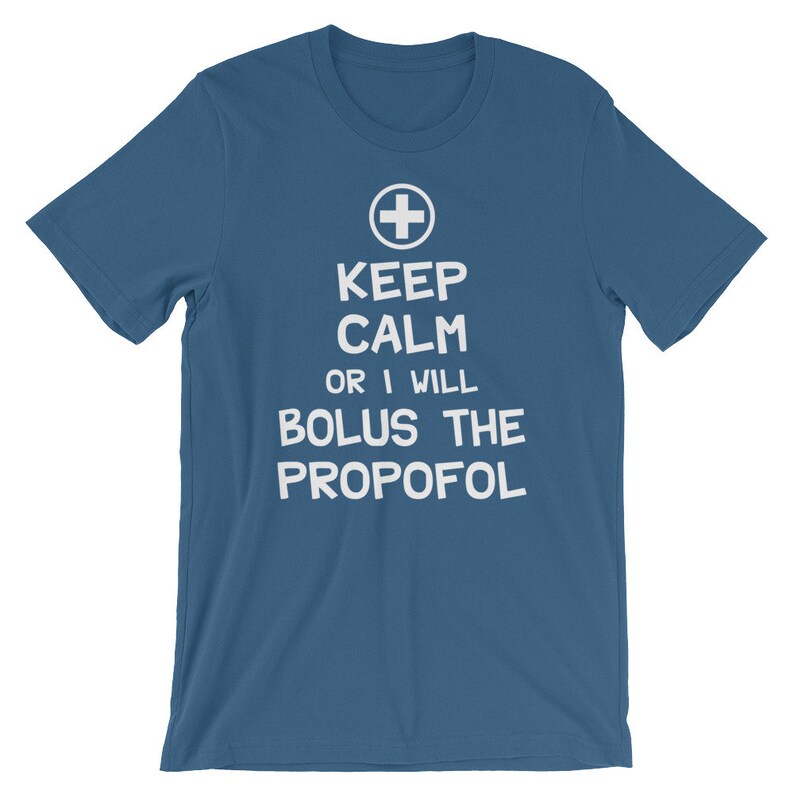 Puede incluir: Una camiseta azul con texto blanco que dice "Keep Calm or I Will Bolus the Propofol" y un signo m&aacute;s blanco.