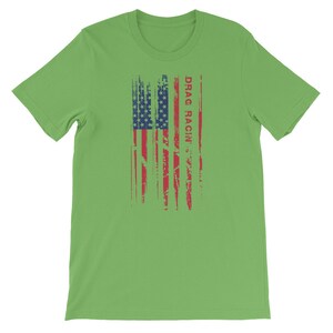 May include: A green t-shirt featuring a distressed American flag design and the text "DRAG RACIN'" in red.