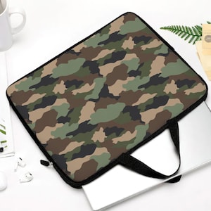 Könnte beinhalten: Eine Laptop-Hülle im Camouflage-Muster mit schwarzem Reißverschluss und Griff. Die Hülle hat ein Muster aus grünen, braunen und beigen Formen. Ein silberner Laptop ist teilweise in der Hülle zu sehen.
