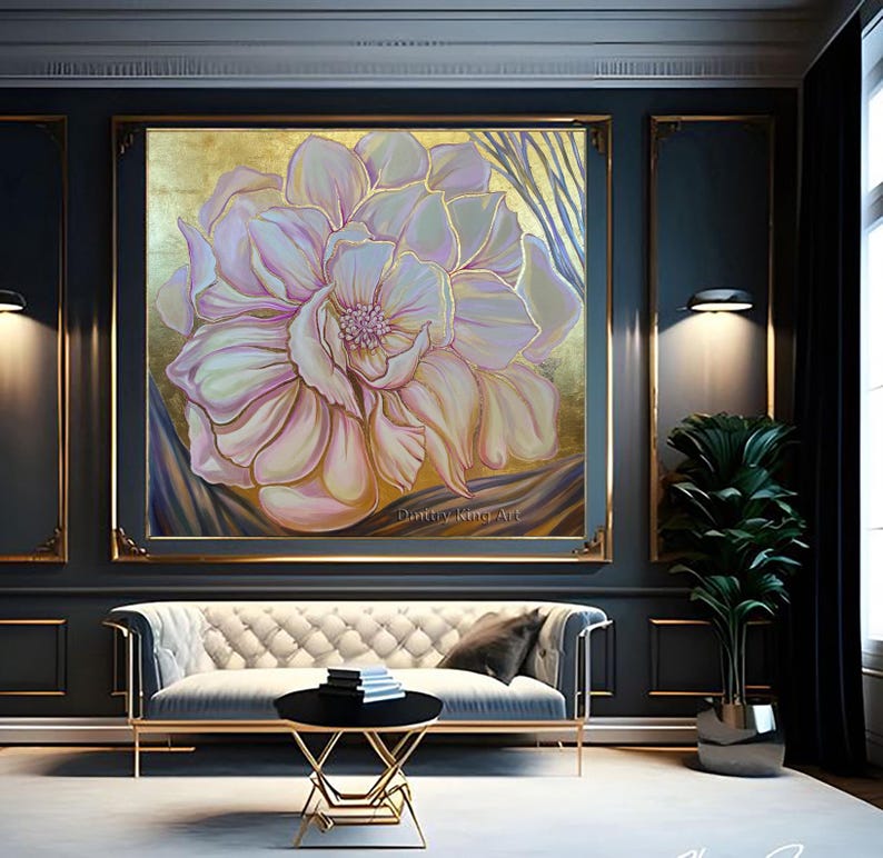May include: A large, abstract painting of a pink flower with gold accents. The painting is framed in a gold frame and hangs on a dark gray wall. The painting is in a modern living room with a white sofa and a gold coffee table.