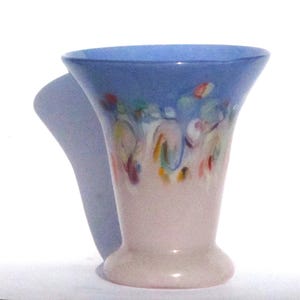 May include: A decorative vase with a flared top and a rounded base. The top is a light blue, transitioning to a pale pink base. Colorful abstract paint strokes adorn the upper portion of the vase.