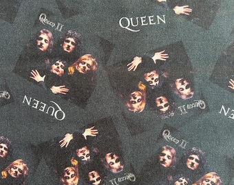 May include: A dark green fabric featuring a repeating pattern of the Queen II album cover. The print displays the four band members in a dark, moody composition with the white text QUEEN and Queen II printed repeatedly across the surface.