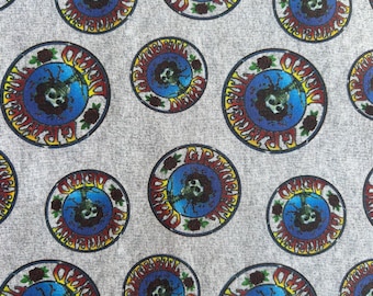 Puede incluir: Una tela gris claro con un patrón repetitivo de logotipos circulares de Grateful Dead. Cada emblema circular muestra un gráfico central de calavera rodeado por un fondo azul, rosas rojas y el texto amarillo Grateful Dead.