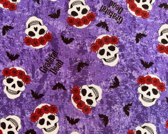 Puede incluir: Una tela morada con un patrón repetitivo de calaveras blancas con coronas de rosas rojas, pequeños murciélagos negros y el texto Grateful Dead impreso en negro. El fondo presenta un diseño morado moteado y texturizado en todo el material.