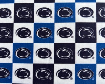 May include: A fabric pattern featuring a repeating checkerboard design in alternating squares of white, navy blue, and royal blue. Each square contains a centered black or white oval logo depicting the profile of a Nittany Lion mascot head.