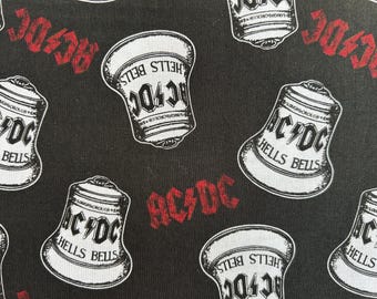 May include: Black fabric featuring a repeating pattern of white bells with the text AC/DC and HELLS BELLS printed on them. The design also includes the red AC/DC logo scattered between the bells, creating a consistent graphic print across the surface.