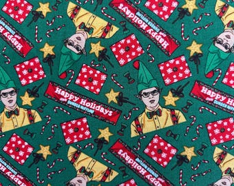 May include: A green fabric featuring a repeating pattern of Dwight Schrute wearing a green elf hat, red gift boxes with white snowflakes, yellow stars, candy canes, and red banners with the text Happy Holidays from Dunder Mifflin.