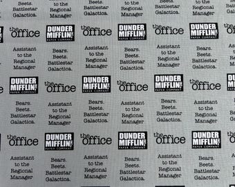 May include: A light gray fabric featuring a repeating pattern of black text and logos. The print includes the Dunder Mifflin Paper Company logo, the text 'the office', and the phrase 'Bears. Beets. Battlestar Galactica. Assistant to the Regional Manager.'